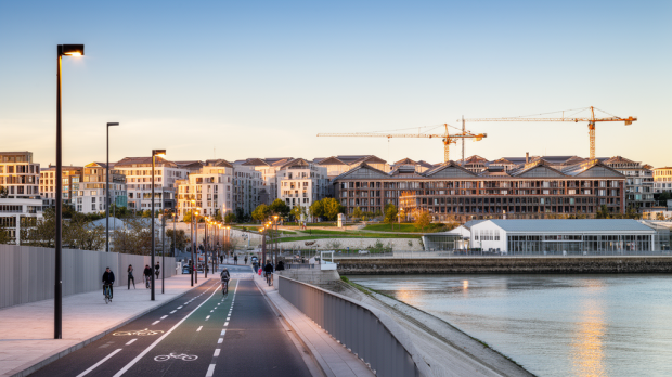 Vue réaliste de l’île de Nantes en transformation avec logements récents, chantiers, berges et piétons à distance